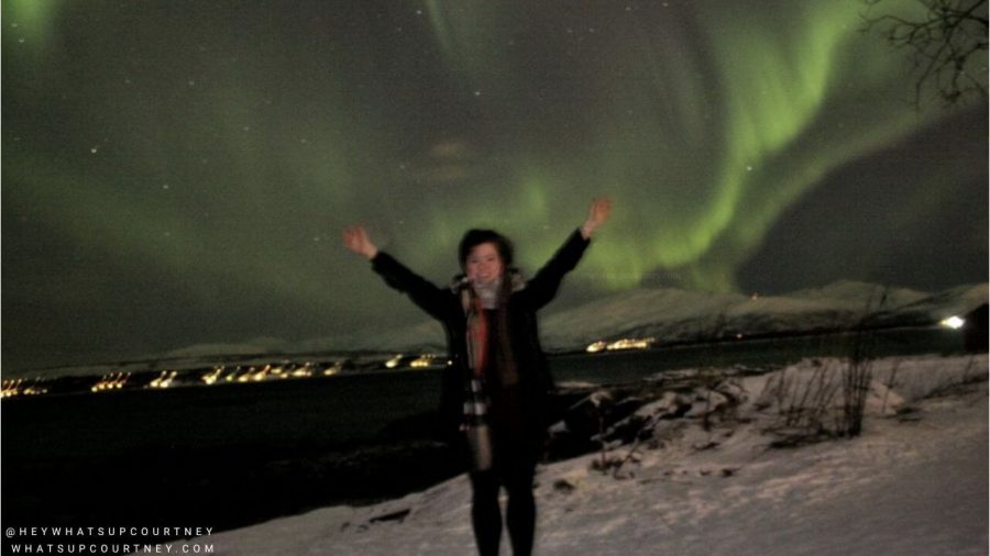 Courtney posing with northern lights in the sky( aurora borealis) in Tromso Norway