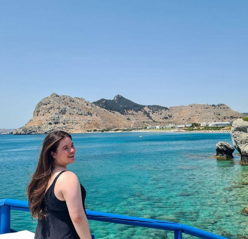 Courtney from whatsupcourtney.com by a church and beach in Rhodes Greece