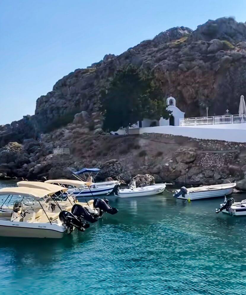 boats and church in st pauls bay rhodes, part of the reason of is lindos rhodes worth visiting