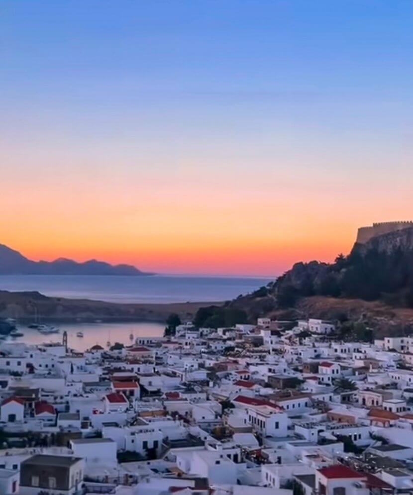 sunset view of lindos rhodes and white rooftop houses
